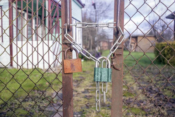 Dois cadeados velhos e uma corrente em uma cerca enferrujada — Fotografia de Stock