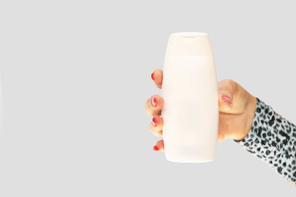 Mano de hembra con uñas rojas sosteniendo una botella de plástico blanco — Foto de Stock