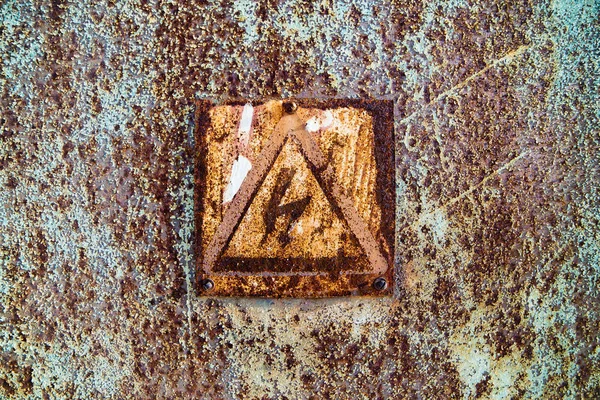 Old rusty tin surface with warning sign of high voltage — Stock Photo, Image