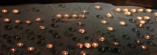 Beaucoup de petites bougies votives sur un sable dans une boîte de support spéciale — Photo