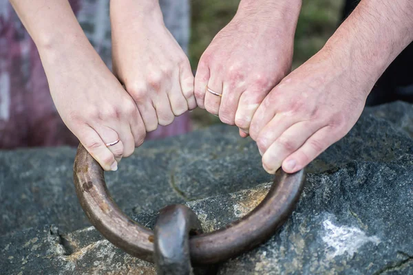 Vrouw en man's armen met trouwringen trekken een grote metalen ring — Stockfoto