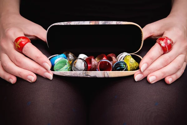 Woman's hands holding tray with many various colorful rings — Stock Photo, Image