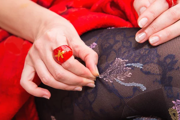 Woman's legs with beautiful stockings and hand with red ring — Stock Photo, Image