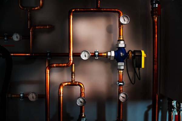 Valve actuator in a boiler room with copper pipes and thermomete