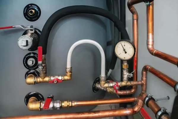 Válvulas, manómetro y tubos de cobre en una sala de calderas — Foto de Stock