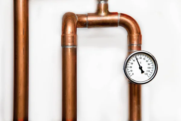 Трубы системы отопления с термометром на белой стене — стоковое фото