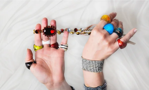 Kvinnans händer med många färgstarka glas ringar, armband och nekla — Stockfoto