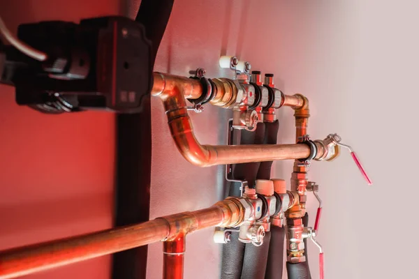 Tubos y válvulas de cobre en una luz roja — Foto de Stock