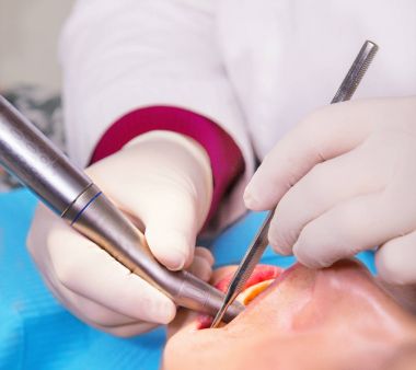 Dişçi eller eldiven ve araçları bir hastanın ağzına