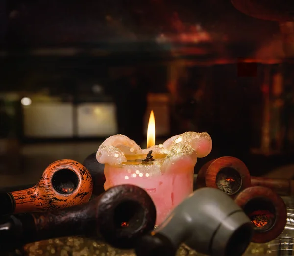 Свечное пламя и пять труб с углем на столе вечером — стоковое фото