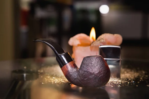 Flamme de bougie, briquet et tuyau sur une table le soir — Photo