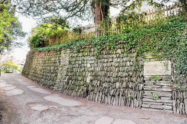 Pendiente de piedra con valla de madera en él y el camino viejo — Foto de Stock