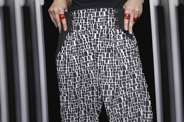 Manos de mujer con anillos rojos sujetando pantalones — Foto de Stock