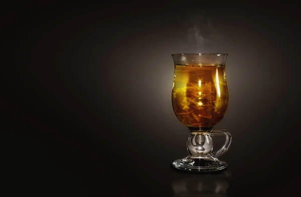 Glass with a hot herbal tea in a dark background — Stock Photo, Image