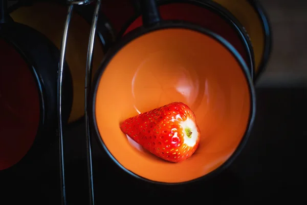 Morango maduro em uma xícara de laranja em um suporte de xícaras em um b preto — Fotografia de Stock