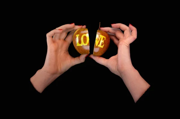 Women hands hold two parts of apple with the LOVE inscription — Stock Photo, Image