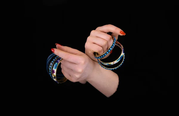 Blaue Armbänder in Frauenhänden auf schwarzem Hintergrund — Stockfoto