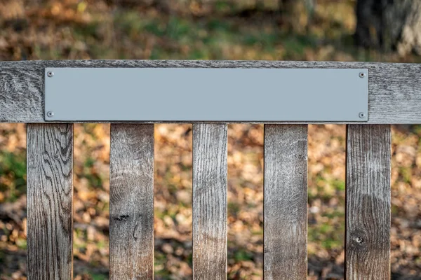 Detail of wooden bench with a grey metallic label — Stock Photo, Image