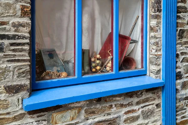 Blaues Fenster eines alten Hauses mit verschiedenen Gartenattributen darin — Stockfoto