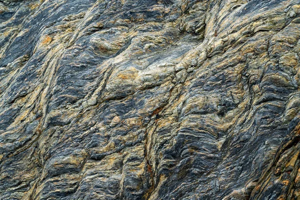 Black cracked rock on the sea shore — Stock Photo, Image