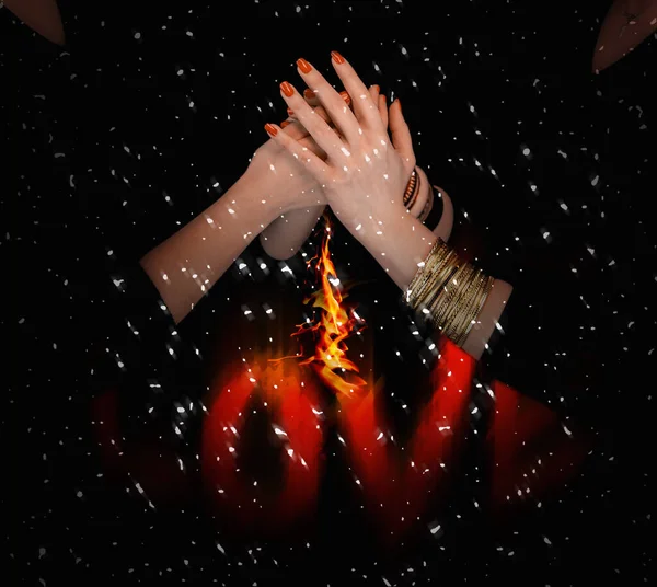 女人的手拿着金色的手镯 把其他女人的手握在火焰上 降雪的黑色背景 — 图库照片