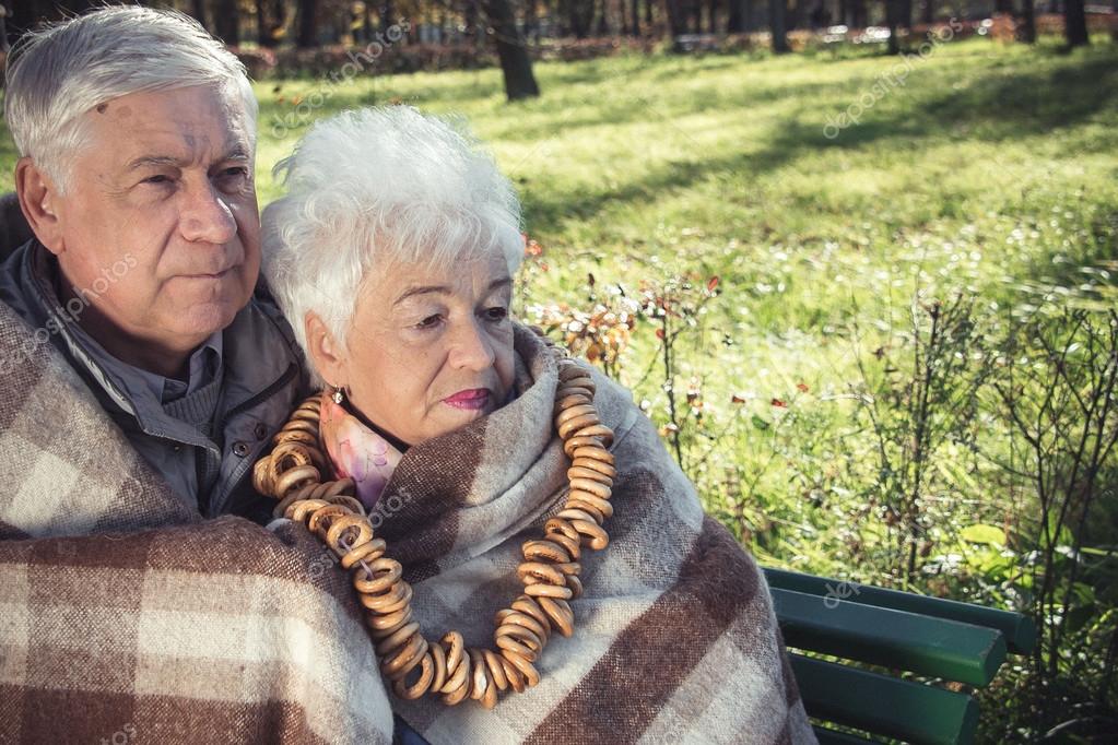 Schöne, glückliche alte Menschen sitzen im herbstlichen Park