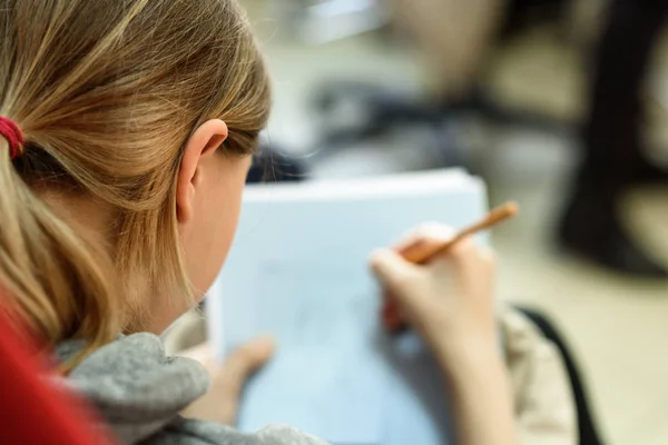 Girl draws a pencil in the album-view from the back close-up