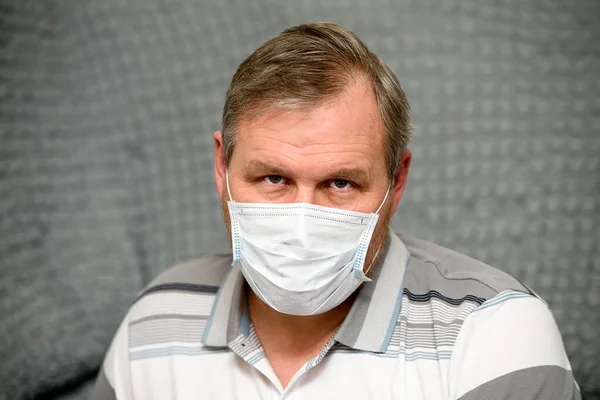 A man in a medical mask, quarantine and self-isolation-a tired look on his face.