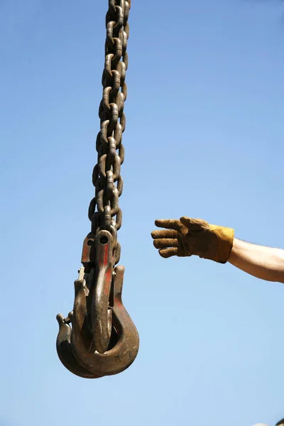 Рука неизвестного рабочего с промышленными крановыми цепями — стоковое фото