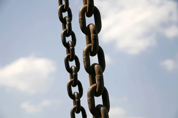 Cadenas oxidadas de hierro viejo colgando en el aire contra el cielo azul —  Fotos de Stock