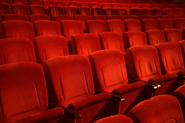 Red colored empty movie theater chairs in row