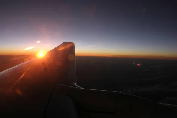 Flygplansvinge flyger över moln när utsikten från fönstret i solnedgången — Stockfoto