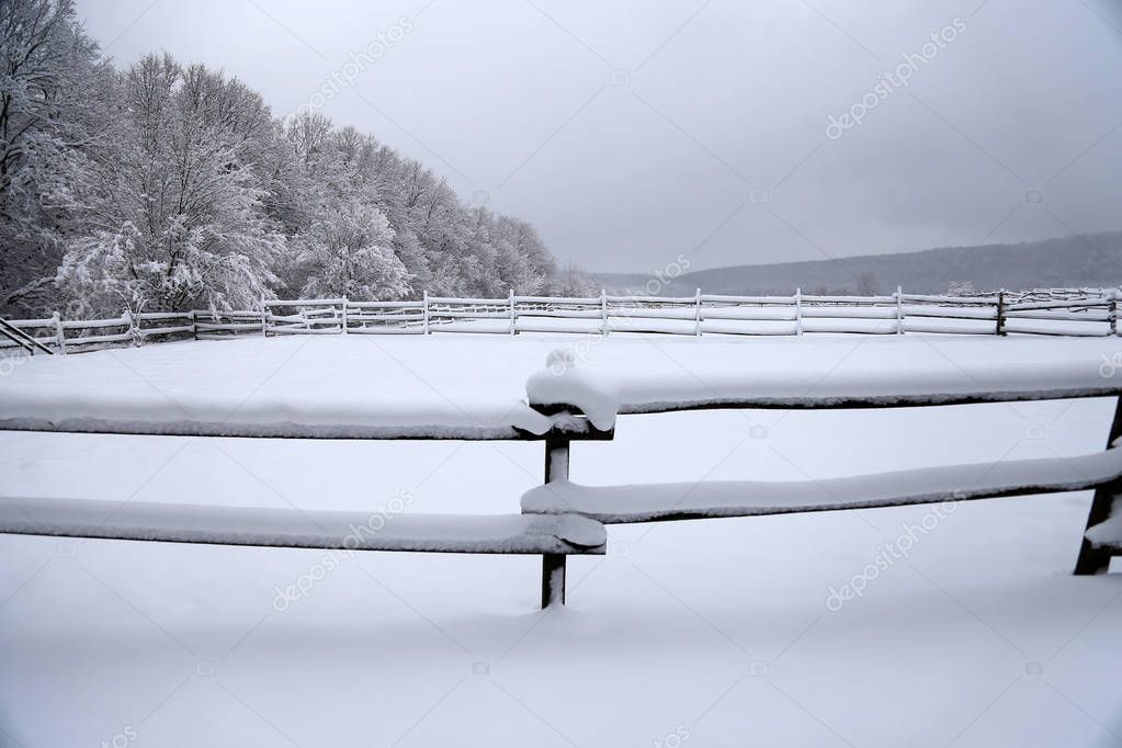Fabulous winter landscape with fresh snow on rural wooden fence at animal farm