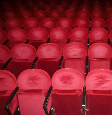 Tiyatroda klasik boş kırmızı koltuklar. Ziyaretçisi olmayan bir salon. Sığ alan derinliği