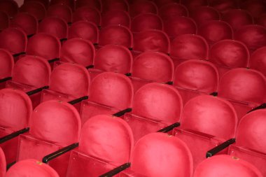 Tiyatroda klasik boş kırmızı koltuklar. Ziyaretçisi olmayan bir salon. Sığ alan derinliği