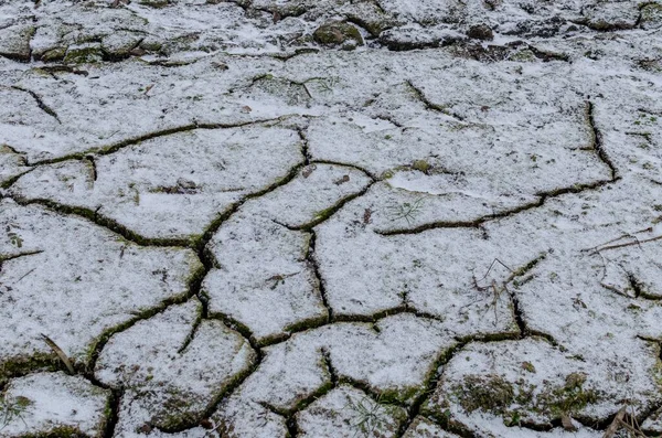 Kış mevsiminde kar ile çatlamış toprak dokusu