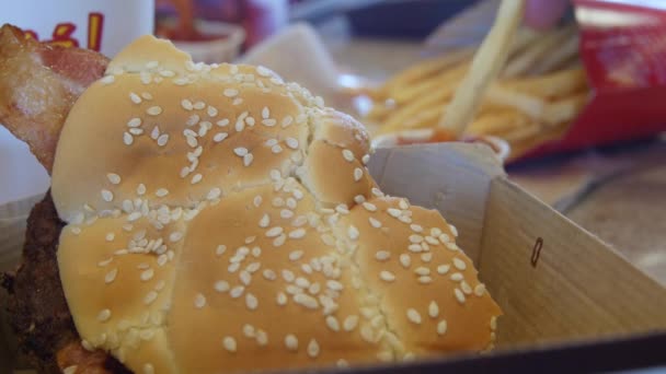 Un uomo mangia patatine fritte e hamburger a pranzo — Video Stock