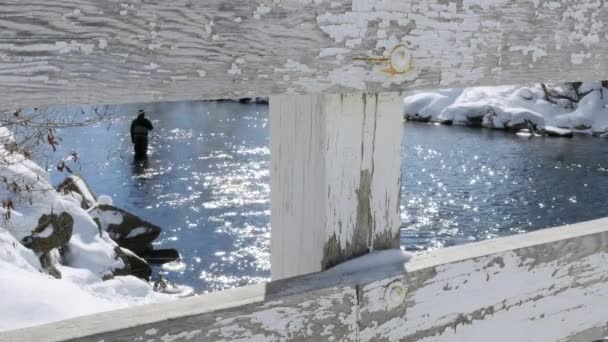 Homem pesca durante o inverno em um rio — Vídeo de Stock