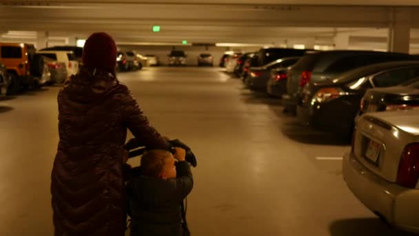 Una madre e bambino spingere passeggino attraverso il garage — Video Stock