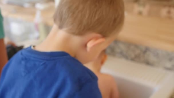 Una madre dando a un bebé un baño en el fregadero de la cocina — Vídeos de Stock