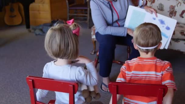 En mor som läsande till små barn i förskolan — Stockvideo