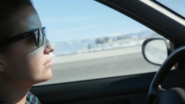 Une femme conduit une voiture à travers les montagnes enneigées — Video