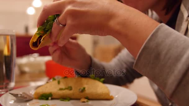 Žena jí skořepinový mexické tacos na večeři — Stock video