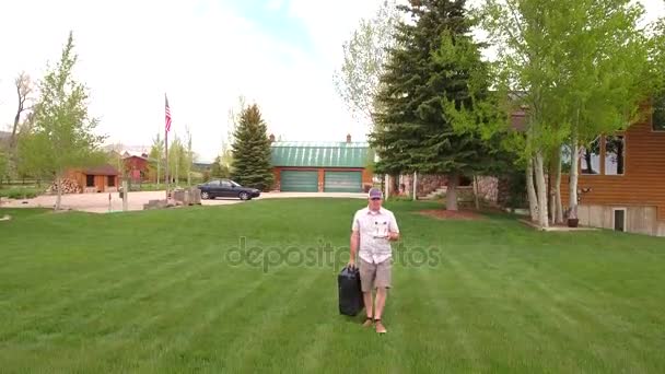 Человек сажает беспилотник в своем дворе с дистанционным управлением — стоковое видео
