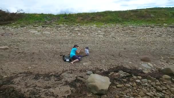 Madre jugando con el niño en la playa rocosa — Vídeo de stock