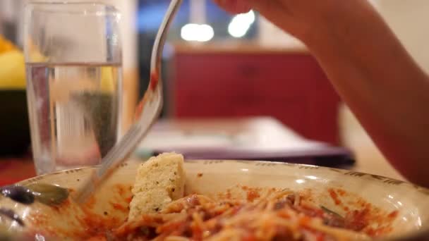 Een vrouw eet spaghetti een de keukentafel — Stockvideo