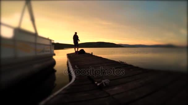 Человек рыбачит на красивом горном озере — стоковое видео