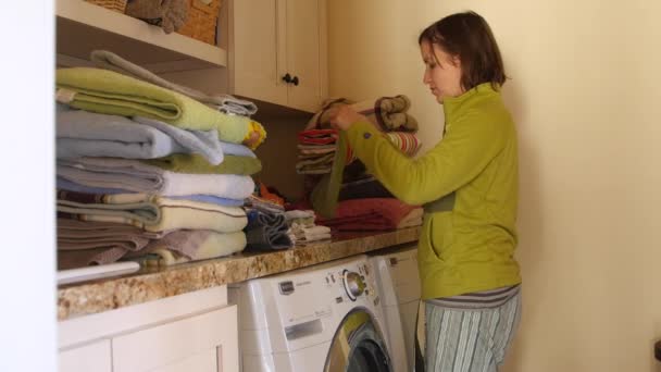 Een moe moeder plooien stapels van Wasserij in kamer — Stockvideo