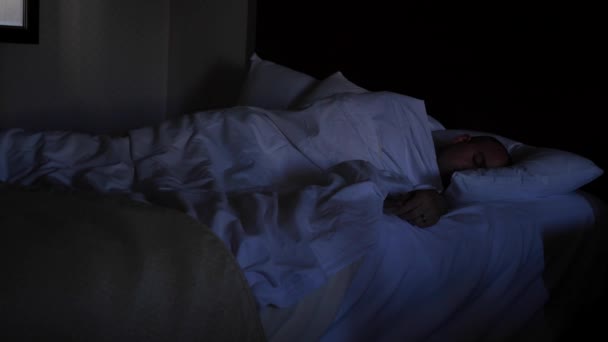Bir exhasuted adam bir yatakta uyuyor — Stok video