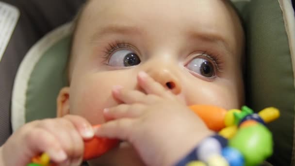 Baby zit in een autostoel spelen met speelgoed — Stockvideo